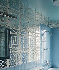 Blue bathroom with patterned mirrored wall, shower, and turquoise ceiling.