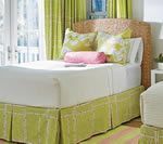 Bed with woven headboard, white sheets, and lime green bed skirt and curtains.