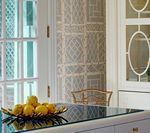Kitchen with a countertop, lemons in a gold bowl, and a trellis-patterned wall.