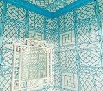 White framed mirror in a small room with blue trellis-patterned wallpaper and trim.