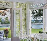 Sunroom with green patterned wallpaper, white furniture, and a view of a body of water.