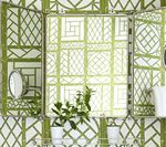 Green lattice wallpaper frames a mirrored medicine cabinet with plants.