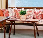 Wooden bench with patterned pillows; small table with potted plant.