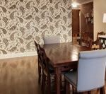 Dining room with paisley wallpaper, a dark wooden table, and upholstered chairs.