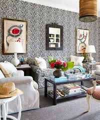 Living room with patterned wallpaper, artwork, couch, coffee table, and lamps.