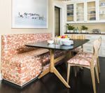 A dining nook with a floral-upholstered bench, a black table, and wooden chairs in a kitchen.