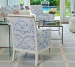 Armchair with blue and white patterned fabric in a bright living room, focused on the chair's back.