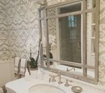 Bathroom with patterned wallpaper, marble countertop, large mirror, and sink.
