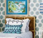 Bedroom with patterned wallpaper, artwork, bamboo headboard, and pillows in shades of blue.