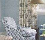 Blue patterned armchair in a room with patterned curtains.