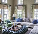 Living room with neutral walls, blue and green accents, and large windows with curtains and shades.