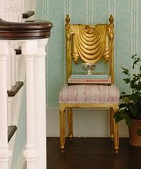 Gold ornate chair with books and plant near staircase.
