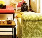 Interior with green patterned sofa, red ottoman, and Asian-style tea set.