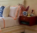 Bedroom with a bed, nightstand, floral arrangement, and patterned bedding.