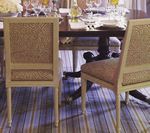 Two beige dining chairs with patterned backs and seats, set at a dark wooden table in a dining room.