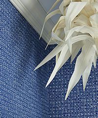 White, abstract ceiling light against blue patterned wallpaper.