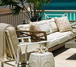 Outdoor seating area with white and wood-toned furniture, cream cushions, and ocean view.