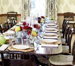 Long, formal dining table set with place settings and floral arrangements.