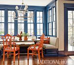 Dining room with blue window frames, orange chairs, and a built-in bench.