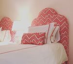 Bed with white linens, coral zigzag headboard and decorative pillows.