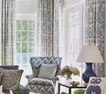 Living room with patterned curtains, armchair, and lamp. Blue, gray, and white color scheme.