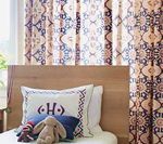 Bed with patterned curtains; pillow with monogram, stuffed rabbit and socks.