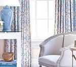 Living room with blue accents: patterned curtains, a blue vase, white furniture.
