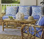 Rattan patio furniture with blue cushions and patterned pillows on a porch.