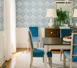 Dining room with patterned blue and white wallpaper, blue chairs, and a dark wood table.