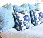 Blue patterned throw pillows on a white bed.