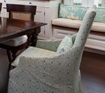 Upholstered chair with blue floral fabric, in front of a dining table and built-in bench.