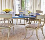 Dining room with blue oval table, cream chairs, and sheer curtains.