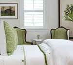 Bedroom with white bedding, green accents, and a framed print on the wall.