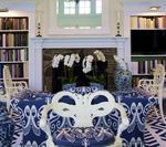 Dining room with blue and white patterned table and chairs, fireplace, bookshelves, and decorative items.