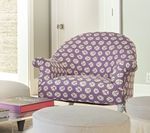 Purple patterned armchair in a light-filled room, with an ottoman and other furniture partially visible.