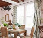 Dining room with wood table, woven chairs, patterned curtains, and a chandelier.