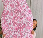 Person holding up floral, pink and white patterned fabric.