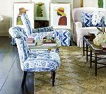 Living room with patterned blue chairs, framed art, and a white sofa.