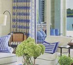 Living room with blue and white decor, white furniture, and a view of water.