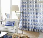 Living room with white armchair, blue patterned curtains, and floor lamp.