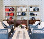Shelves with handbags above seating in a store. Blue and white patterned walls.
