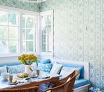 Breakfast nook with blue and white floral wallpaper, built-in bench, and table set with food and flowers.
