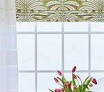 Window with patterned valance, sheer curtain, and vase of tulips.