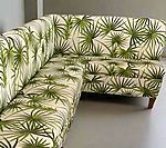 L-shaped sofa upholstered in fabric with a palm leaf pattern in green and white.