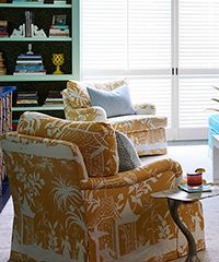 Yellow patterned armchairs near a bright window and bookshelves.