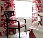 Black chair with pink cushion by a window with red and white patterned curtains.