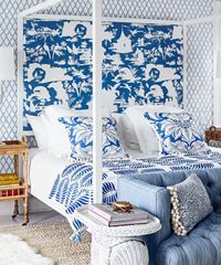 Bedroom with blue and white patterned bedding and headboard, light blue sofa, and textured rug.