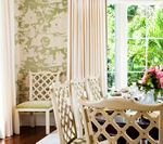Dining room with ornate chairs, floral wallpaper, and large window overlooking greenery.