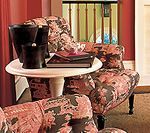 Two floral armchairs with a small table holding objects, set against a red wall.