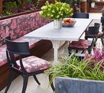 Outdoor dining area with table, chairs, built-in bench, and floral accents.